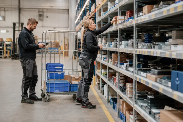 Zwei Mitarbeitende kommissionieren Kleinteile in einem Industrielager